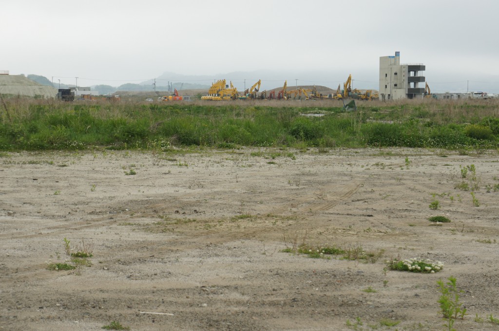 Das Gebäude rechts im Bild steht alleine auf der Ebene, wo früher das Stadtzentrum war. Der Besitzer Yuichi Yonezawa überlebte den Tsunami auf dem Schornstein des Gebäudes, auf der Höhe von 14 m ü. M.