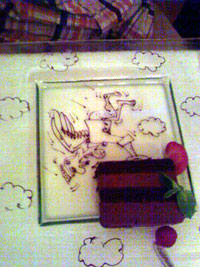 夫が頼んだチョコレートケーキ。大きなガラスのお皿にのっかったケーキを持ち上げる天使（?）はチョコを使ってコックさんが手書きしたもの