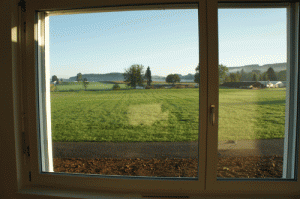新しいアパートのリビングの窓の向こうには牧草地が広がる